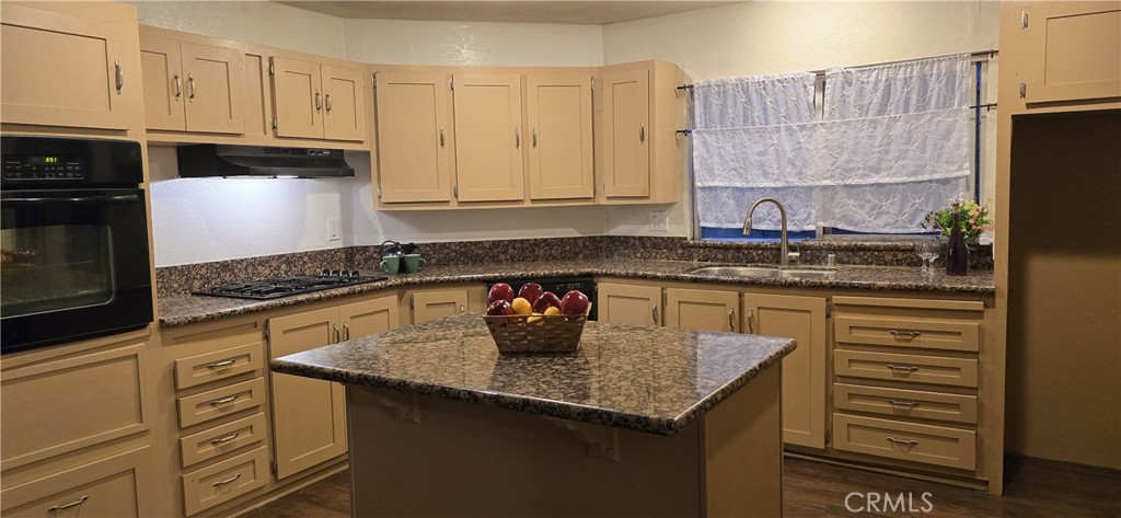 a kitchen with granite countertop a sink a stove and cabinets