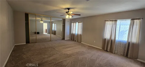 a view of a livingroom with a chandelier fan and windows