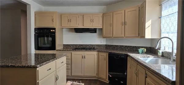 a kitchen with granite countertop a sink stove and cabinets