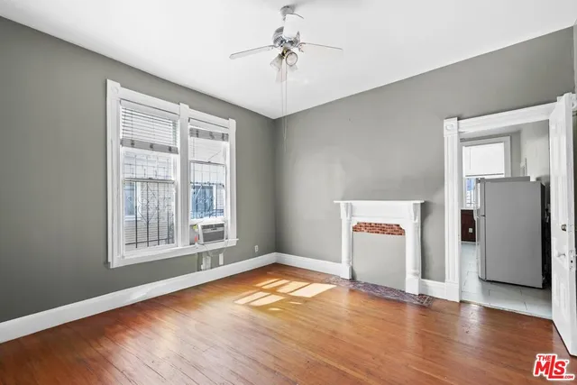 an empty room with wooden floor cabinet and windows