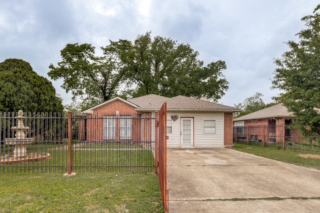 View of front of home featuring a fenced front yard, brick siding, and a shingled roof