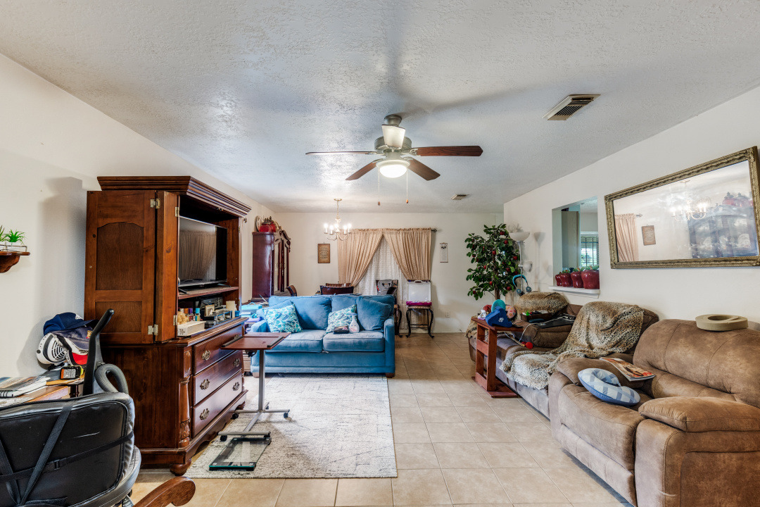 10007 Raymondville Road Houston, TX 77093 - Photo 4 of 19 Living room featuring suspended lighting, a textured ceiling, light tile patterned floors, and a ceiling fan