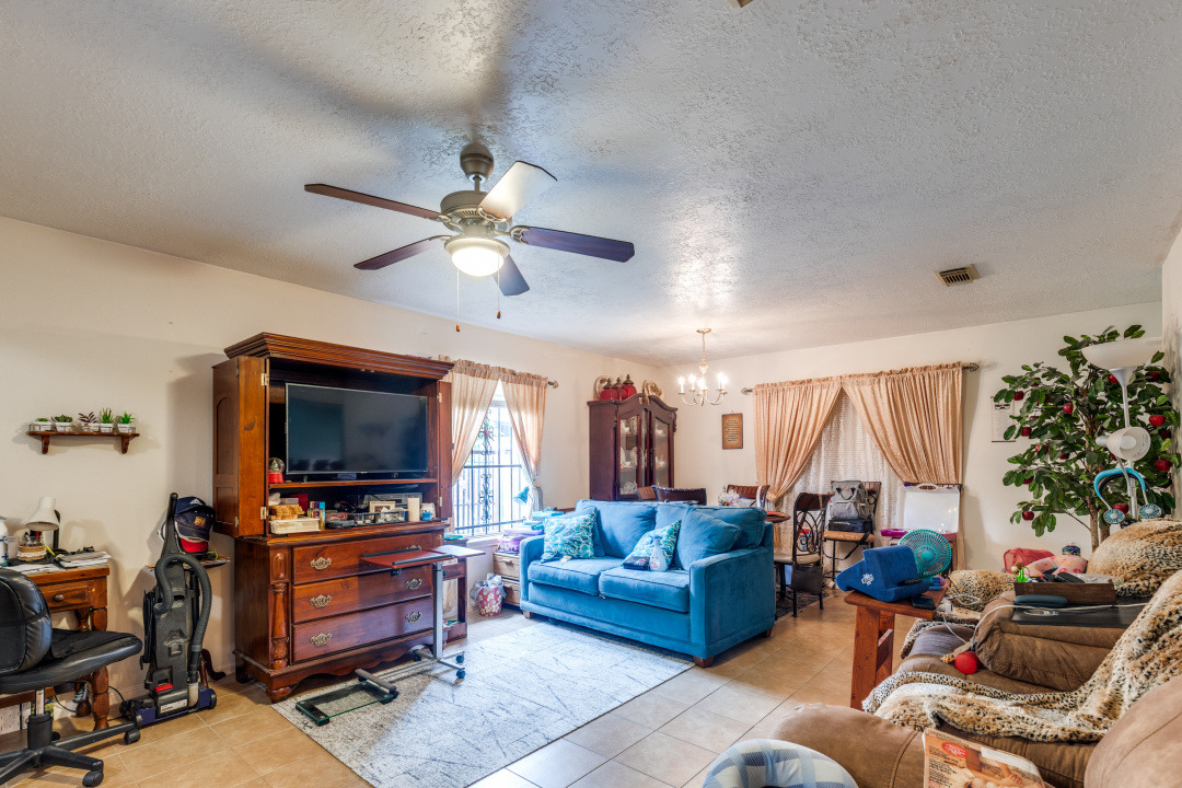 10007 Raymondville Road Houston, TX 77093 - Photo 5 of 19 Living room featuring a chandelier, a textured ceiling, light tile patterned flooring, and a ceiling fan