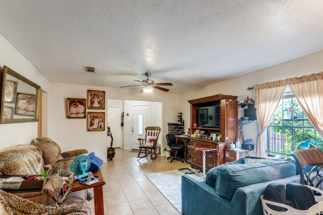 10007 Raymondville Road Houston, TX 77093 - Photo 6 of 19 Living room with a textured ceiling, a ceiling fan, and light tile patterned floors