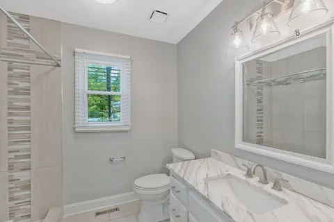 a bathroom with a granite countertop sink toilet and shower