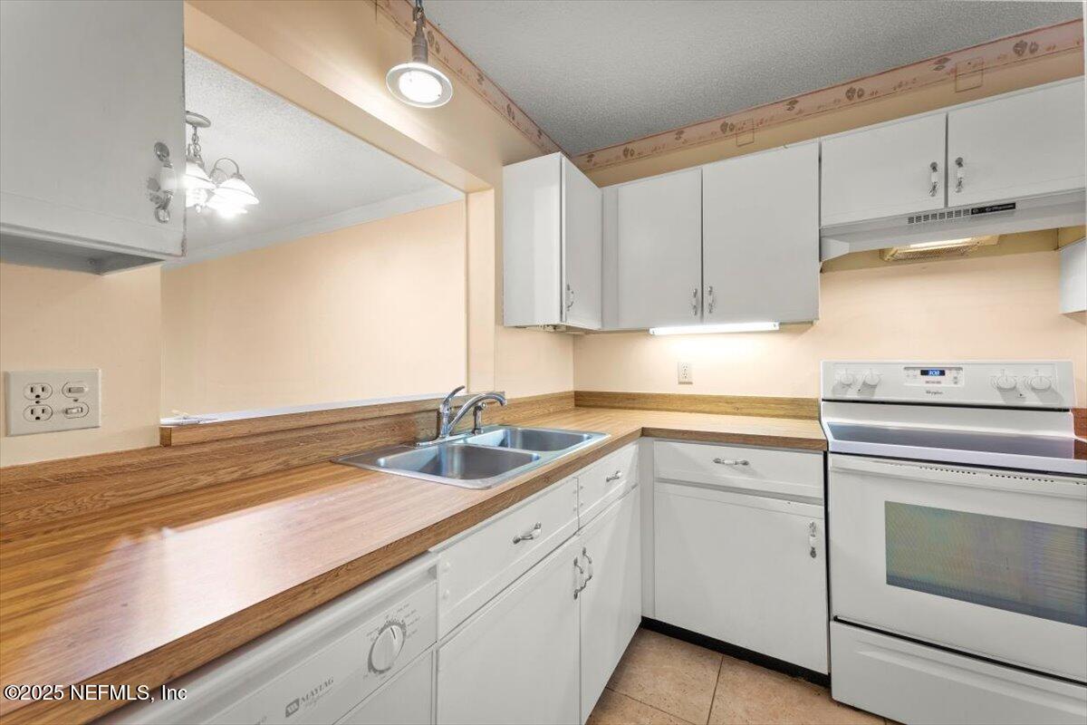 3801 Crown Point Road, Unit 3073 Jacksonville, FL 32257 - Photo 8 of 26 a kitchen with a sink dishwasher a stove and white cabinets with wooden floor
