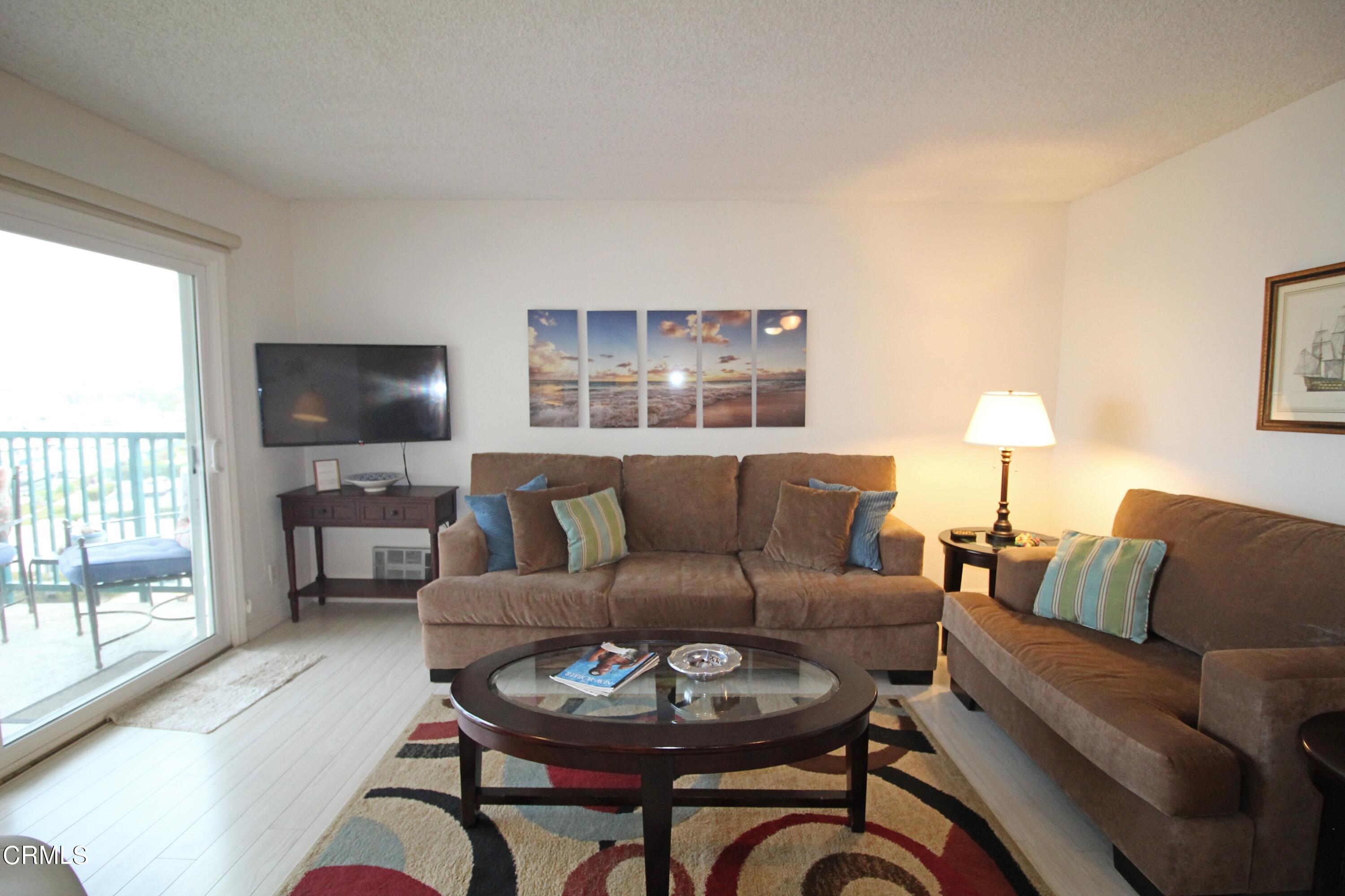 3101 Peninsula Road, Unit 312 Oxnard, CA 93035 - Photo 11 of 26 a living room with furniture a flat screen tv and a large window