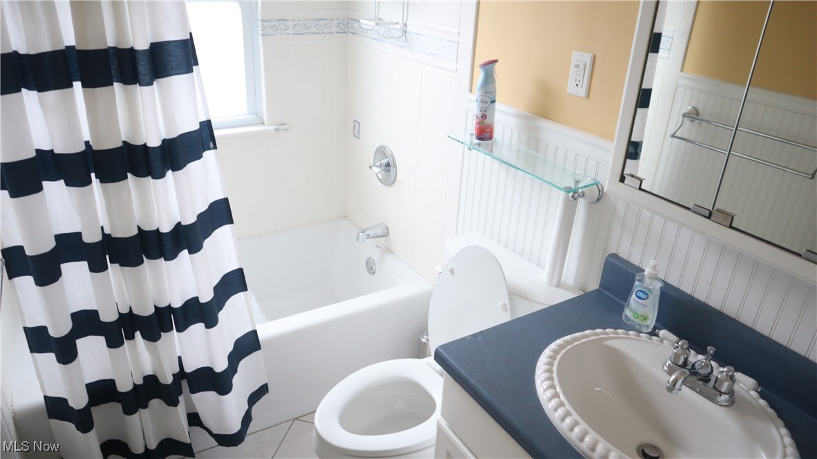 4213 Stonehaven Road Cleveland, OH 44121 - Photo 16 of 21 Full bathroom featuring a wainscoted wall, toilet, vanity, and shower / bath combination with curtain