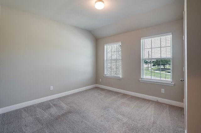 5912 Bursey Road Watauga, TX 76148 - Photo 14 of 23 Spare room featuring light colored carpet, baseboards, and vaulted ceiling