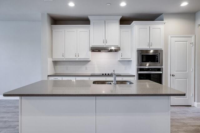 5912 Bursey Road Watauga, TX 76148 - Photo 5 of 23 Kitchen featuring appliances with stainless steel finishes, a sink, white cabinets, a kitchen island with sink, and backsplash