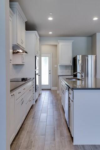 5912 Bursey Road Watauga, TX 76148 - Photo 7 of 23 Kitchen featuring a sink, appliances with stainless steel finishes, dark countertops, an island with sink, and under cabinet range hood