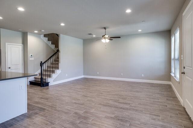 5912 Bursey Road Watauga, TX 76148 - Photo 9 of 23 Unfurnished living room featuring a ceiling fan, plenty of natural light, stairs, light wood-type flooring, and recessed lighting