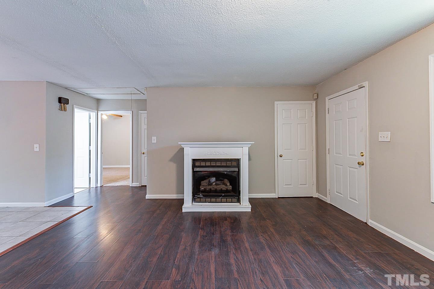 7005 Russell Road Durham, NC 27712 - Photo 4 of 24 a view of an empty room with wooden floor fireplace and a window