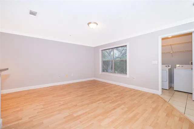 a view of empty room with wooden floor and fan