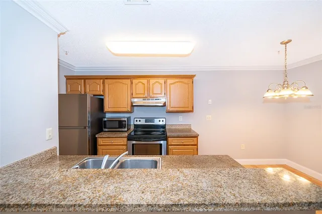a kitchen with stainless steel appliances kitchen island granite countertop a refrigerator and a stove top oven