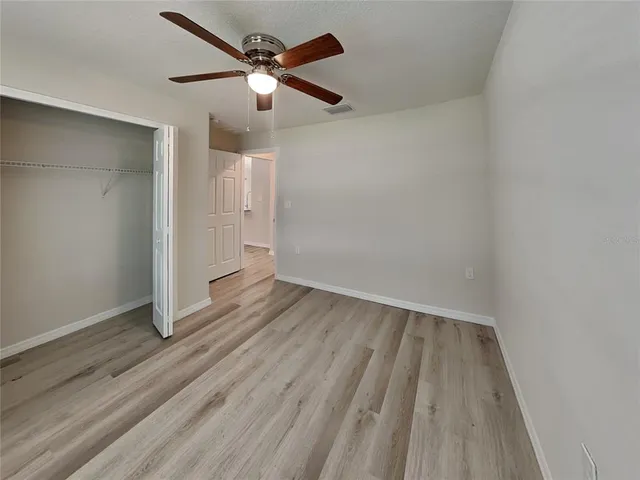 an empty room with wooden floor and a ceiling fan