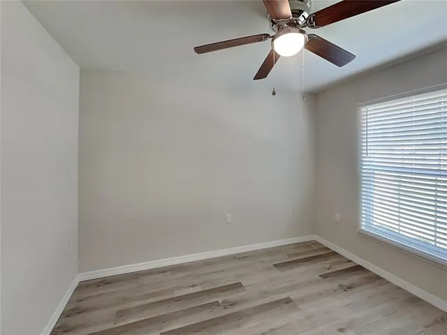 an empty room with a window and a fan