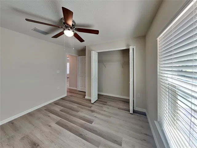 a view of empty room with wooden floor and fan