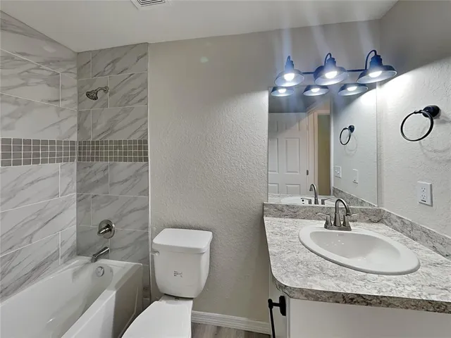 a bathroom with a granite countertop sink a toilet a mirror and shower