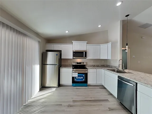 a kitchen with stainless steel appliances granite countertop a refrigerator and a stove top oven