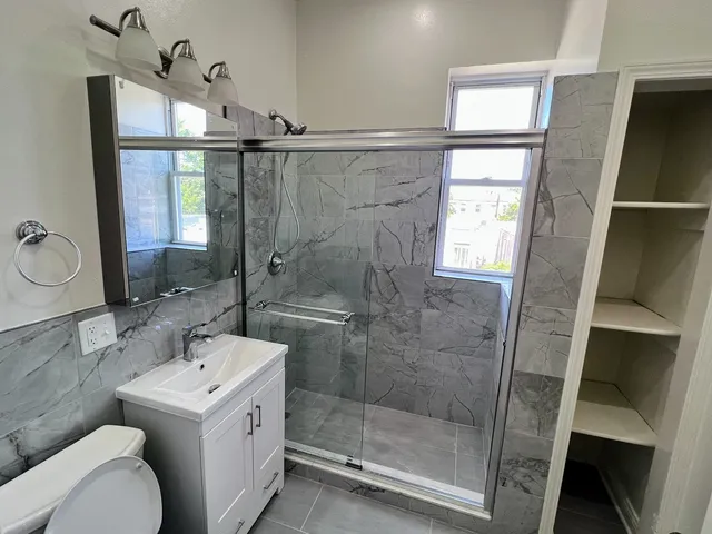 a bathroom with a granite countertop sink toilet and shower