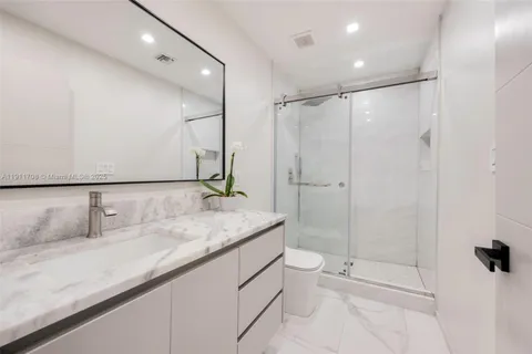 a bathroom with a granite countertop sink a toilet and shower