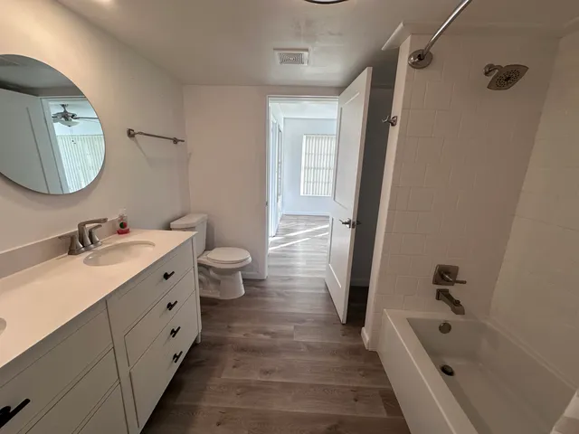 a bathroom with a double vanity sink a toilet a mirror and shower