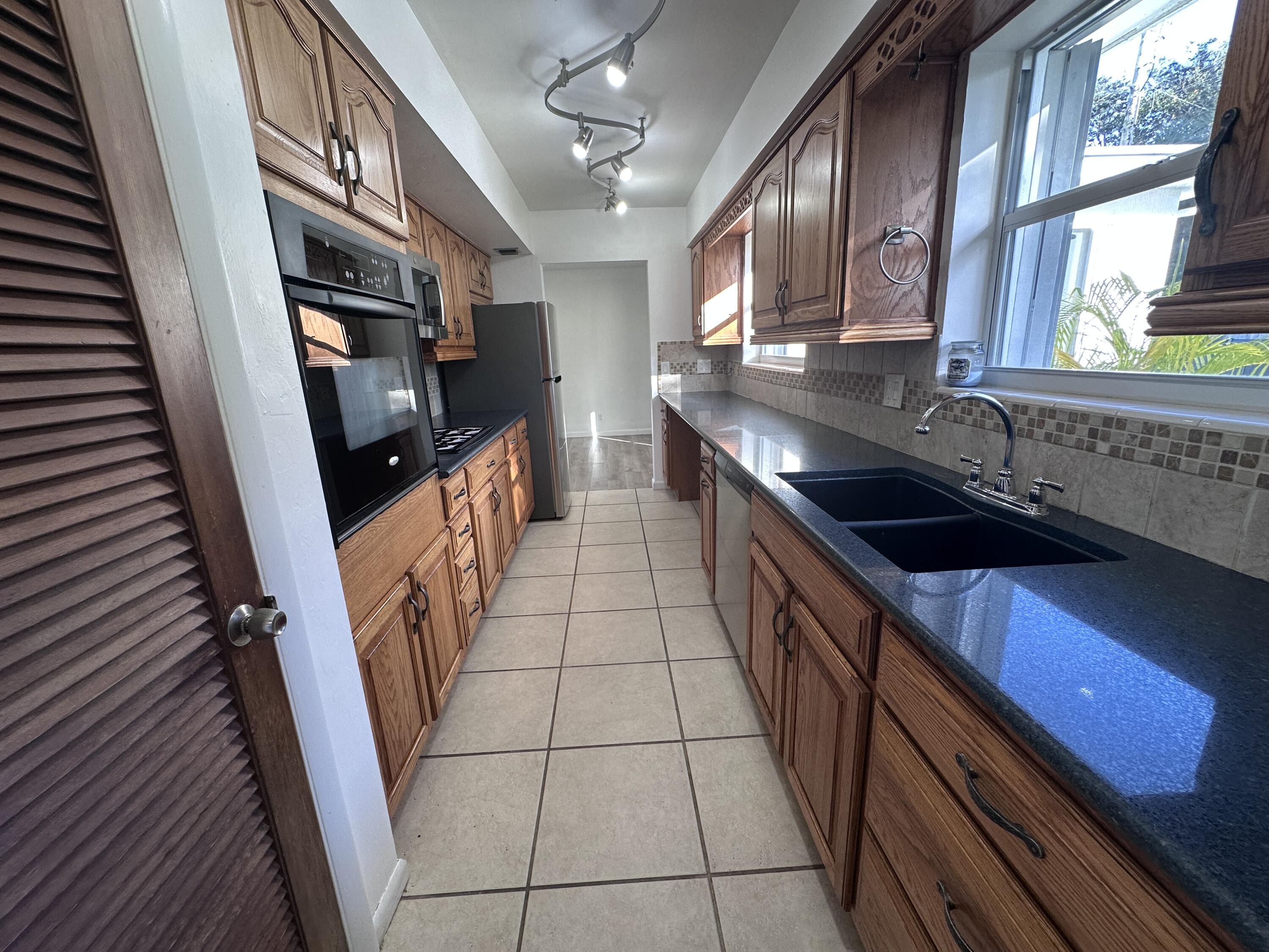 14 Ridgewood Circle Tequesta, FL 33469 - Photo 6 of 24 a kitchen with granite countertop a sink stove and cabinets