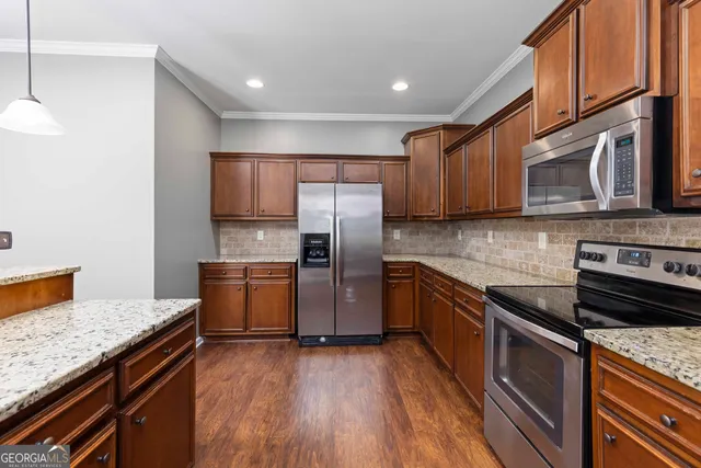 a kitchen with granite countertop wooden cabinets stainless steel appliances and a counter space