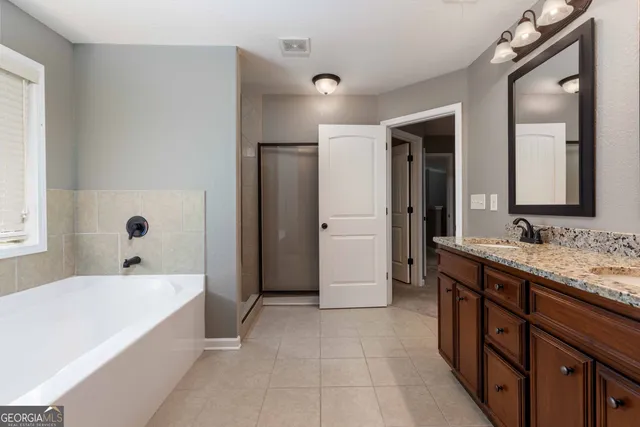 a spacious bathroom with a tub sink and mirror