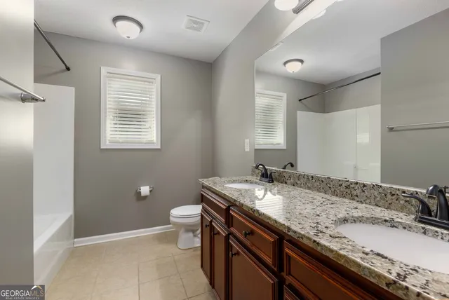 a bathroom with a granite countertop sink a toilet and a mirror