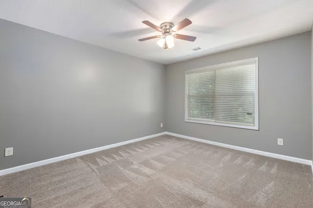 an empty room with windows and fan