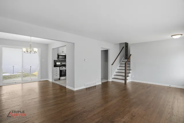 a view of an empty room with wooden floor and stairs