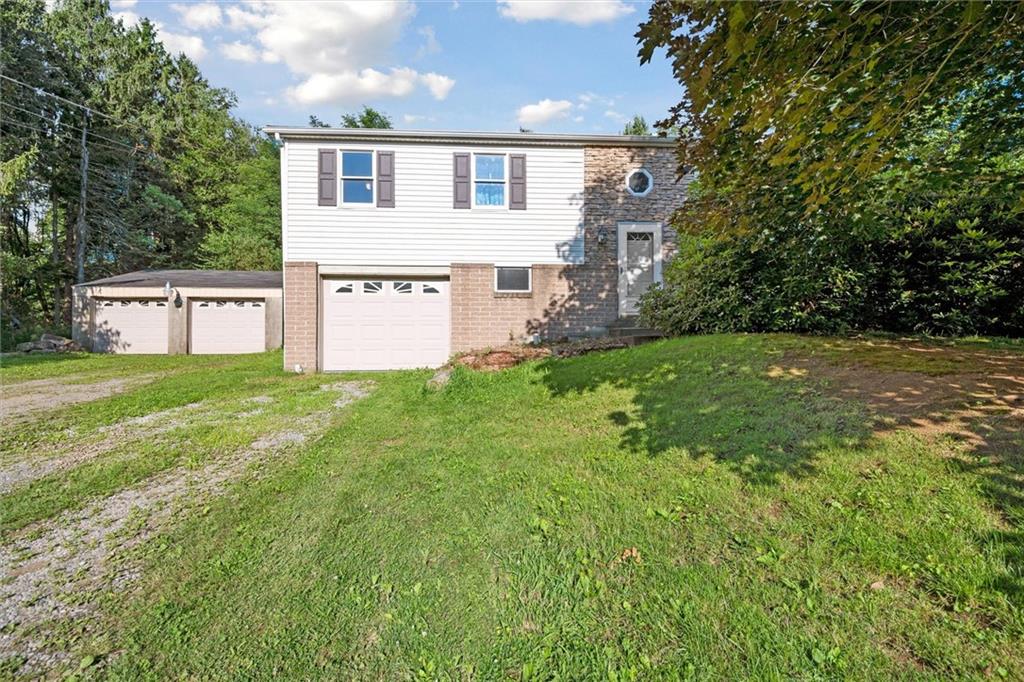 a house that is sitting in the grass with tress in the background