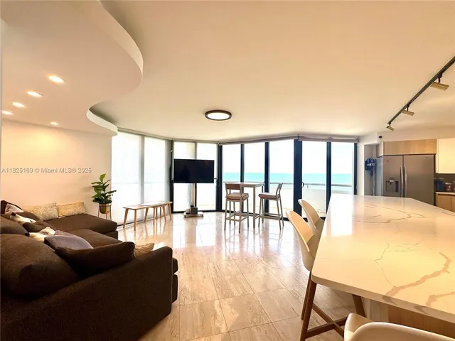 a kitchen with stainless steel appliances a sink a stove top oven a chimney cabinets and a dining table