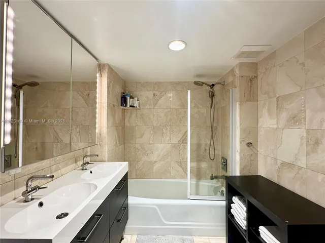 a bathroom with a sink double vanity mirror and a shower