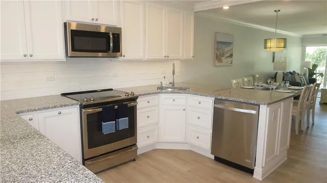 a kitchen with stainless steel appliances granite countertop a stove a sink and a microwave