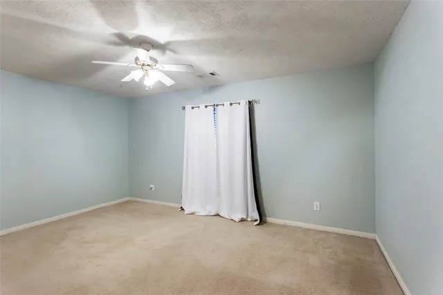 an empty room with a ceiling fan and carpet