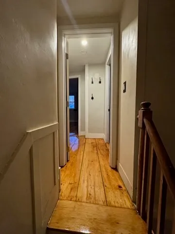 a view of a hallway with wooden floor and staircase
