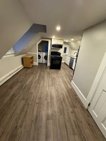 a living room with a bed and a wooden floor