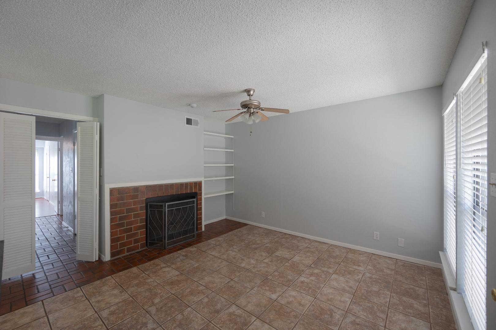 2110 Rio Grande Street, Unit 307 Austin, TX 78705 - Photo 5 of 13 Tiled flooring and a classic brick fireplace anchor this versatile living space.