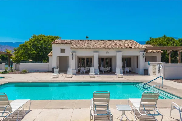 a view of a swimming pool with a lawn chairs under an umbrella