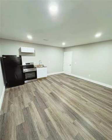 an empty room with wooden floor and stainless steel appliances