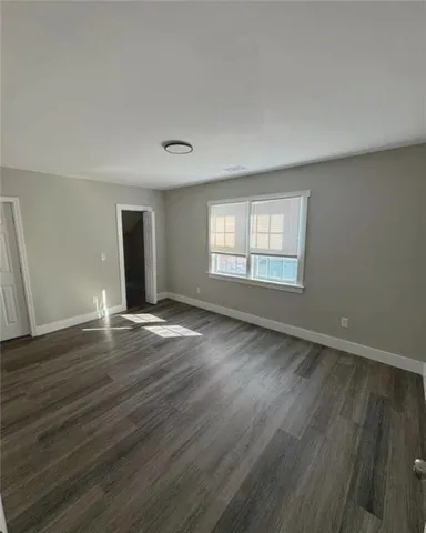 a view of an empty room with wooden floor and window