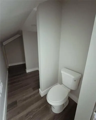 a white toilet sitting next to a wooden floor
