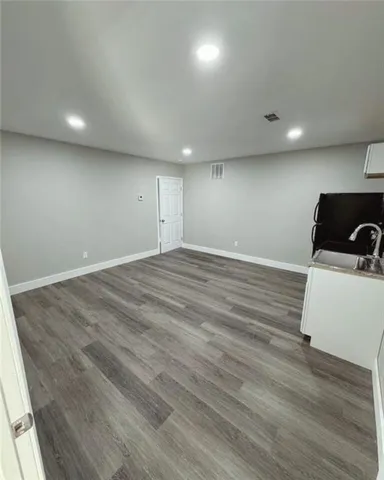 an empty room with wooden floor and kitchen view