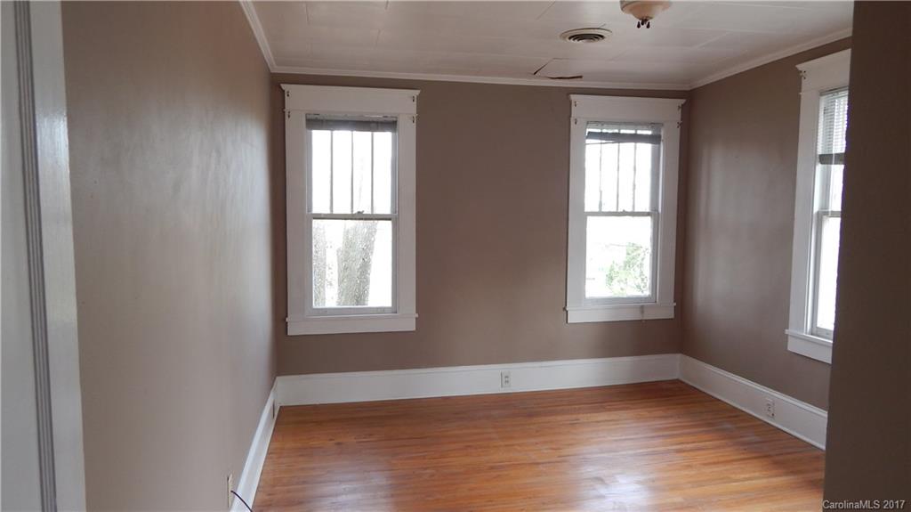 203 Charles Street, Unit A Monroe, NC 28112 - Photo 7 of 10 a view of an empty room with wooden floor and a window