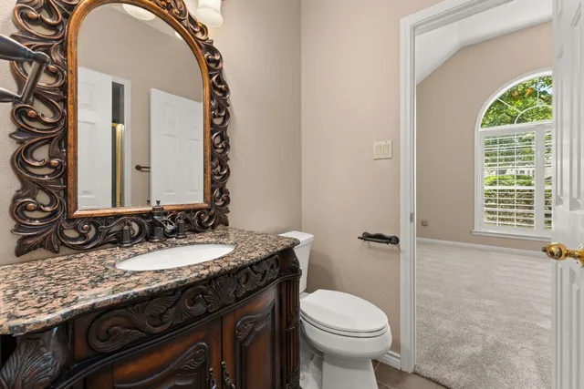a bathroom with a granite countertop toilet a sink and a mirror