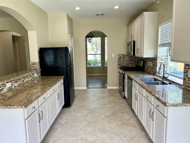 a kitchen with stainless steel appliances granite countertop a stove a sink and a microwave
