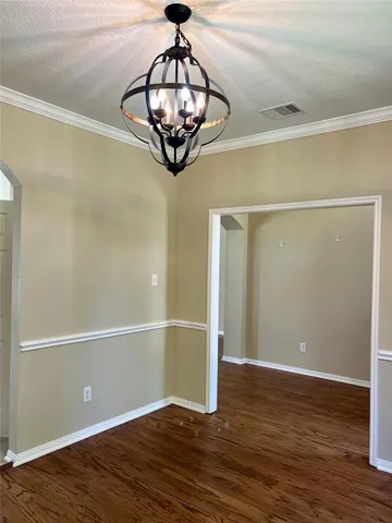 a view of a room with wooden floor chandelier and refrigerator